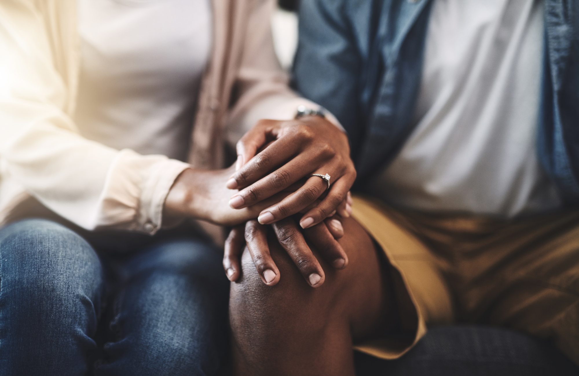 Cropped shot of a man and woman sitting on a sofa and holding hands